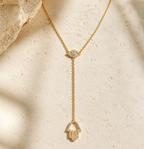 Gold tone Protection Lariat Necklace styled on a natural stone surface.
