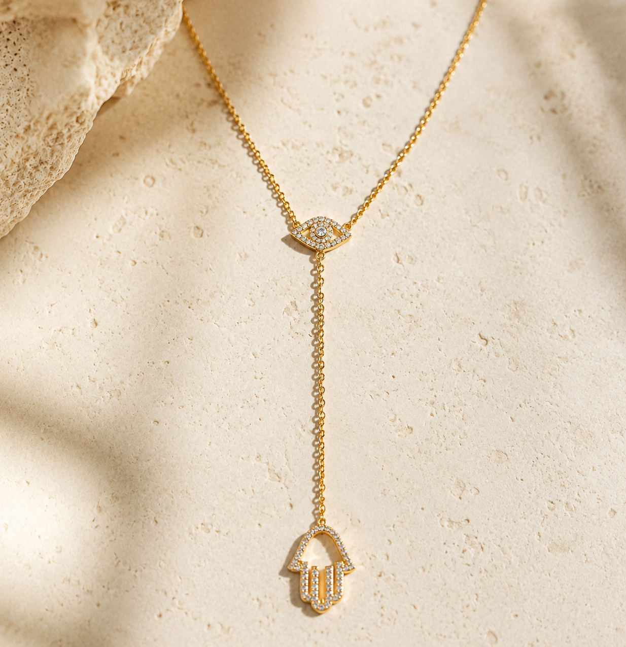 Gold tone Protection Lariat Necklace styled on a natural stone surface.