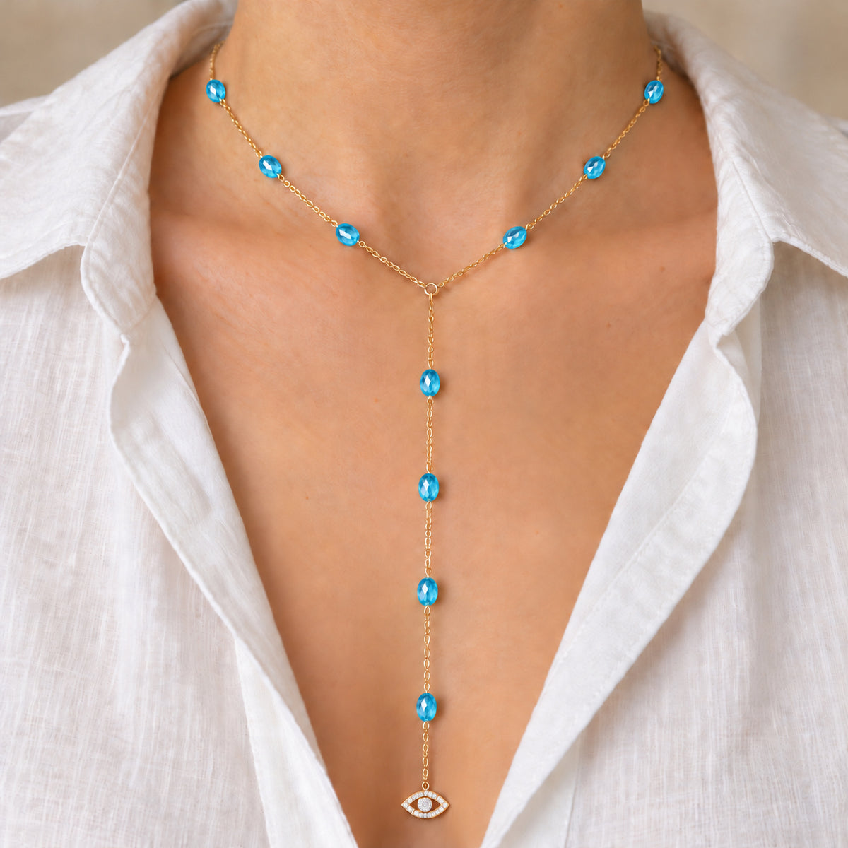 Blue See No Evil Lariat Necklace worn with an open white blouse, cropped below the face.