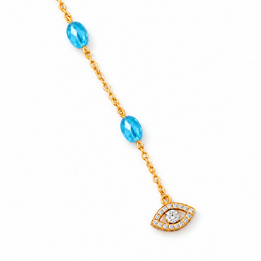 Close-up of blue beads, a gold tone chain, and the pavé CZ evil eye charm on ivory stone.