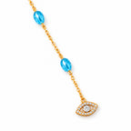 Close-up of blue beads, a gold tone chain, and the pavé CZ evil eye charm on ivory stone.
