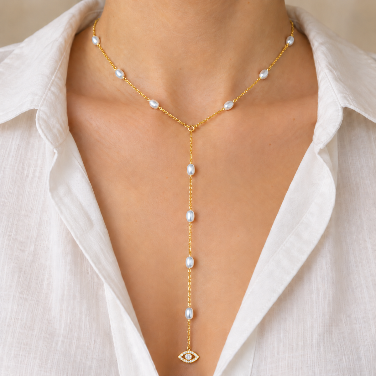 White Pearl See No Evil Lariat Necklace worn with an open white blouse, cropped below the face.
