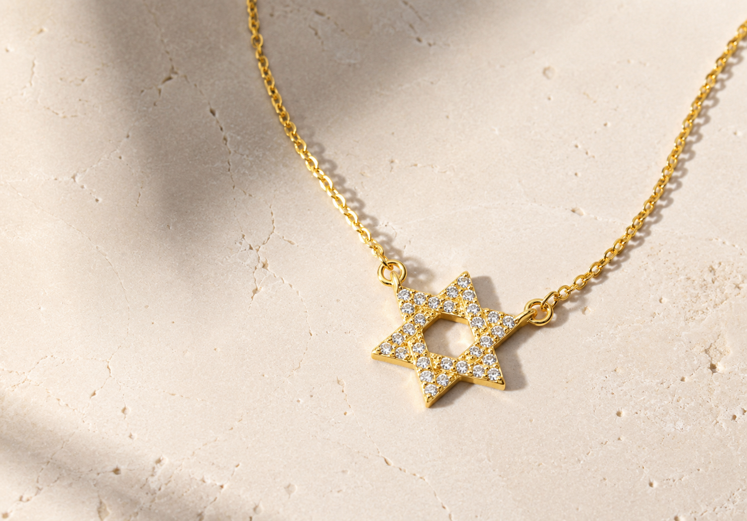 Gold tone Star of David CZ Necklace styled on a neutral stone surface.