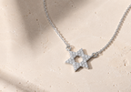 Silver tone Star of David CZ Necklace styled on a neutral stone surface.